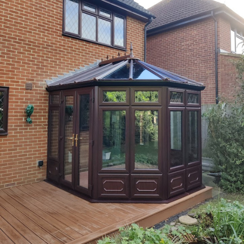 A brown framed glass conservatory on decking