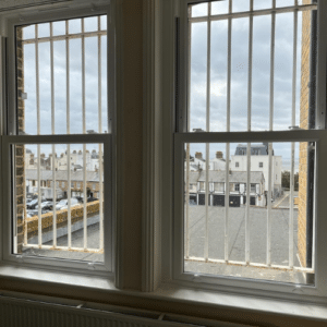 Two double glazed uPVC sash windows with metal railings on the outside.