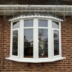 A white uPVC bow window fitted onto some brickwork.