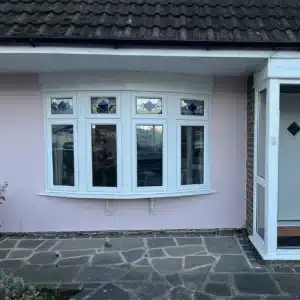 A white uPVC bow window on a pink wall.